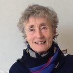 A photo of Di Steeds. An older white woman with short grey hair wearing a blue scarf. 