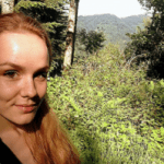 A photo of Dr Sandra Neumann, a white woman with long blond hair against a green background of trees. 
