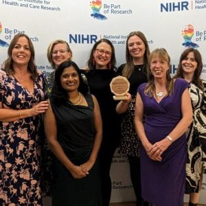 Photo of Associate Professor Emily Henderson, Chief Investigator of the CHIEF-PD trial, and members of the team, smiling and showing the award trophy. 
